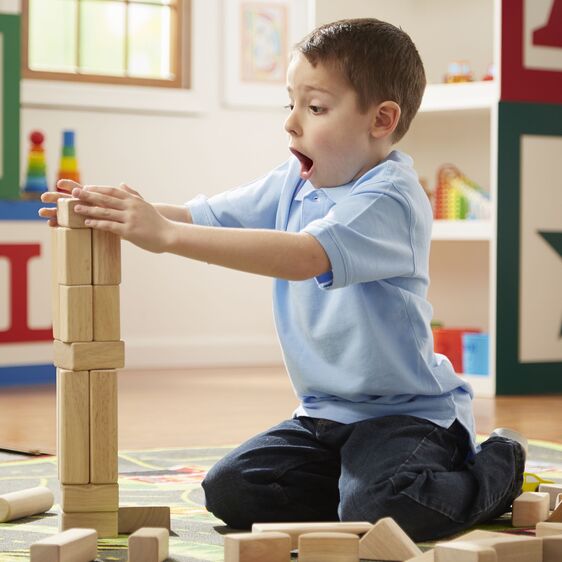Child playing with a tower of wooden blocks from the Wooden Blocks Set for creative hands-on learning and play.