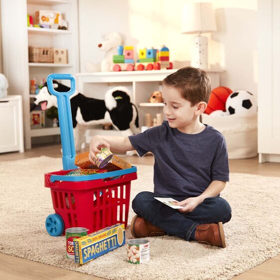 Child playing with the Fill & Roll Grocery Basket filled with play food boxes and cans in a playroom.