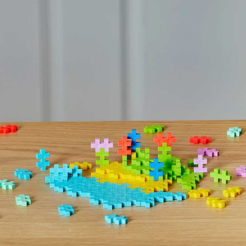 Plus Plus Tropical 240pc colorful building pieces arranged in a tropical flower design on wood surface.