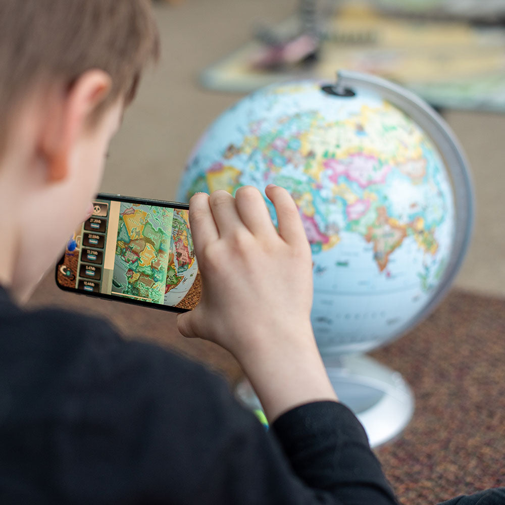 Child exploring educational Kids Globe using augmented reality app on smartphone to discover animals and landmarks.