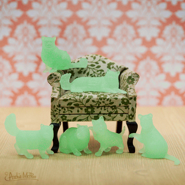Glow Cat soft vinyl glow-in-the-dark cats in assorted styles around a small patterned chair for kids ages 3 and up.