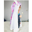 Baby White Unicorn Cape Size 2-3 with colorful mane and silver horn worn by toddler smiling and holding a lollipop.