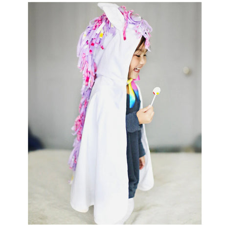 Baby White Unicorn Cape Size 2-3 with colorful mane and silver horn worn by toddler smiling and holding a lollipop.