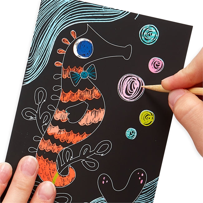 Scratch & Scribble Friendly Fish shows colorful seahorse and bubbles revealed by scratching with wooden stylus on black card.