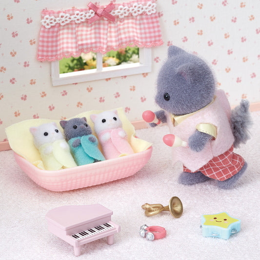 Persian Cat Triplets in cradle with a parent figure holding rattles and miniature toys in a cozy room setting.