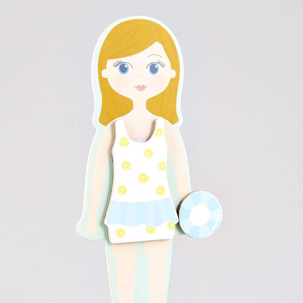 Magnetic Dress Up | Elsie wooden doll wearing a floral swimsuit holding a blue and white rubber ring toy.