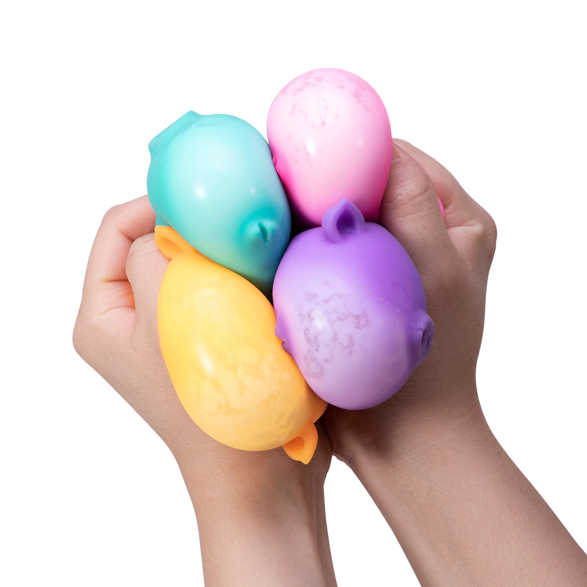 Hands squeezing four colorful NeeDoh Dig It Pig stress balls in pastel blue, pink, yellow, and purple.