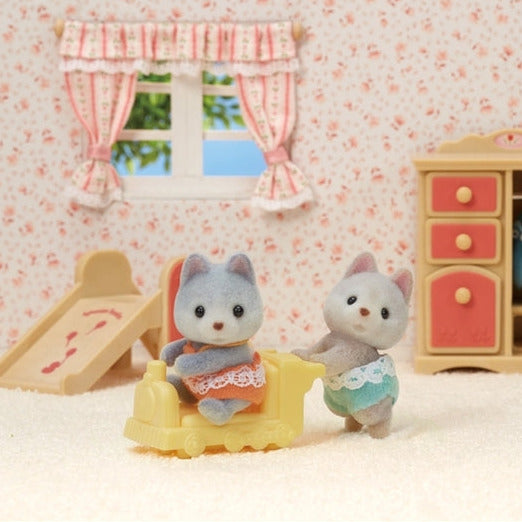 Husky Twins baby figures Amber sitting and Jeremy crawling with a yellow pushcart in a cozy playroom setting