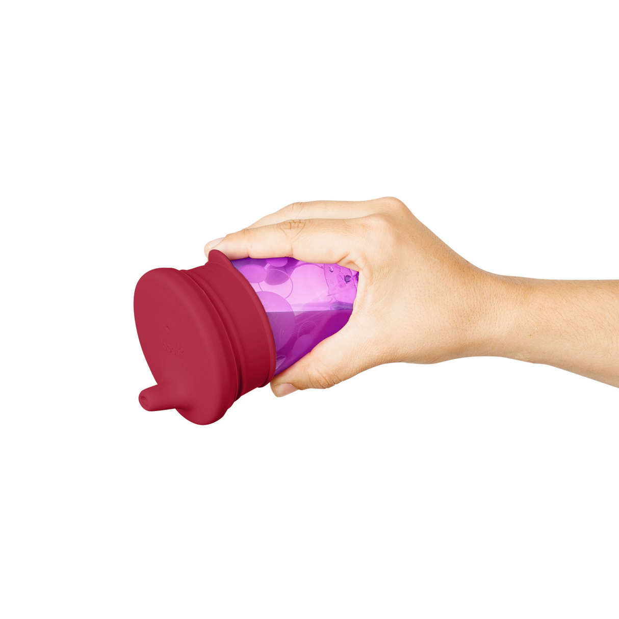 Hand holding a purple cup with a red SNUG Spout Sippy Lids Pinks silicone spill-proof lid attached.
