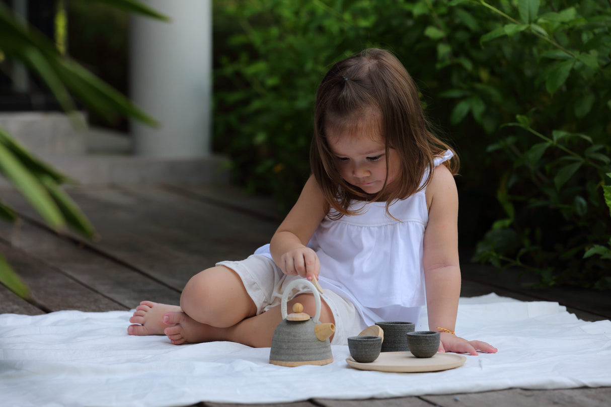 Child playing with Classic Tea Set including teapot, cups, and tray, encouraging imaginative pretend play outdoors.