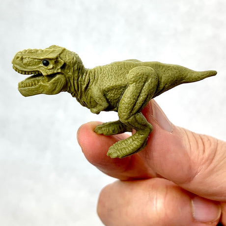 Hand holding a detailed Japanese Eraser T-Rex puzzle eraser shaped like a small green dinosaur.