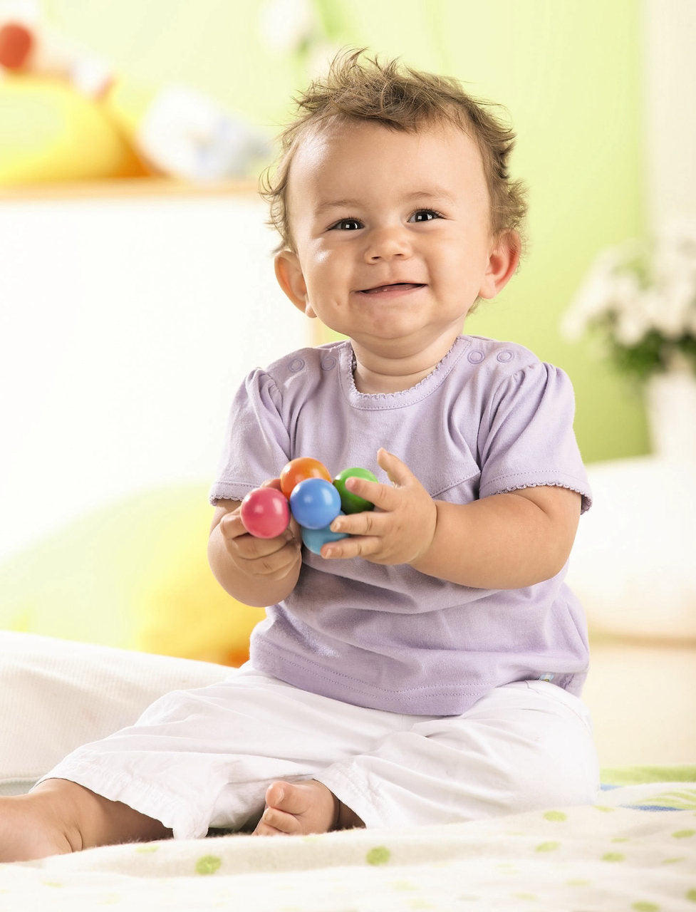 Baby smiling and holding colorful Magica Wooden Clutching Toy made of safe, hand-crafted wooden balls for teething.