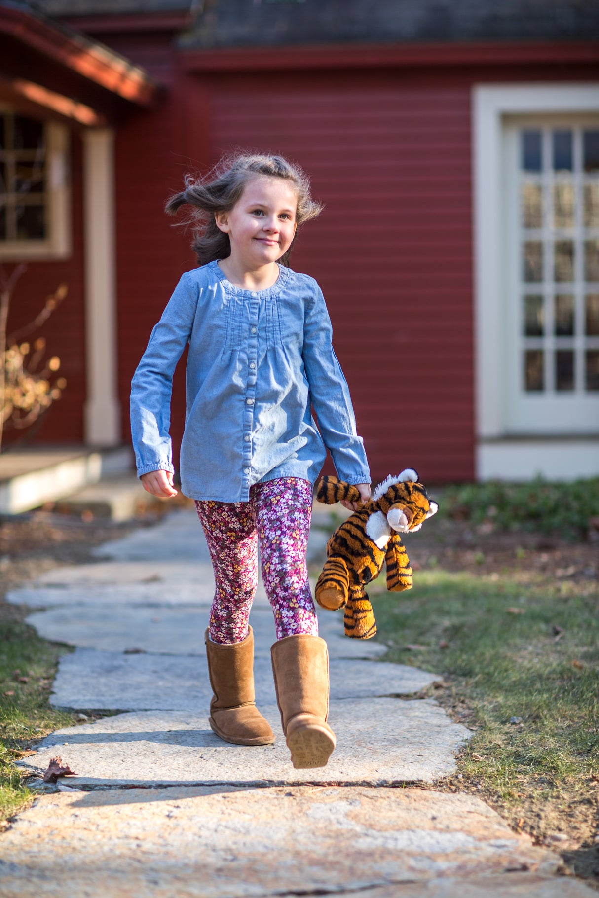 Young girl walking outdoors holding Marshmallow Tiger plush toy for comfort and play.