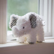 White plush elephant with striped ears sitting on a windowsill, Afrique Elephant Musical toy.