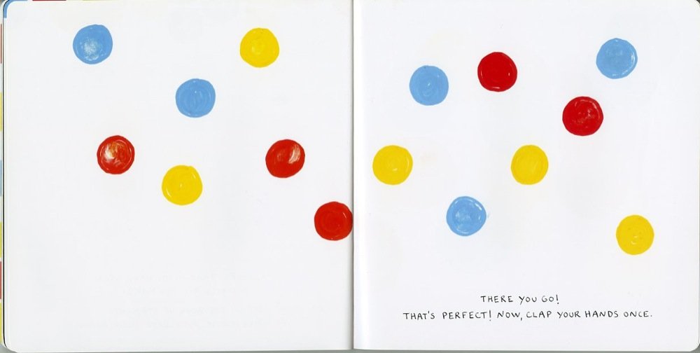 Open pages of Press Here book showing colorful dots on a white background for interactive play and imagination.