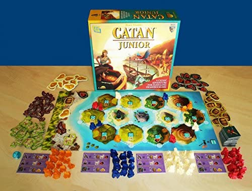 Catan Jr. board game set up with colorful pirate hideouts, ships, resource tokens, and game box for kids age 5+.