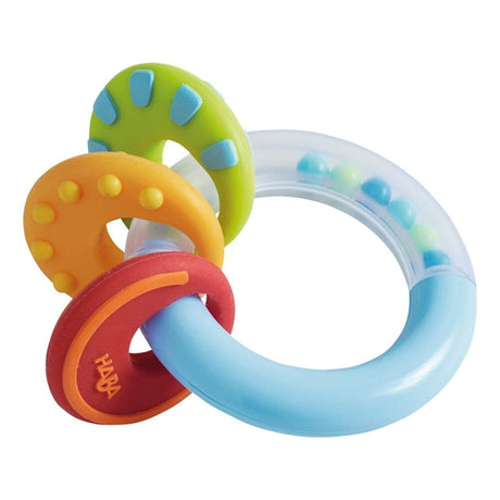 Clutching Nobbi Teether baby toy with colorful textured silicone rings and a rattling BPA-free plastic ring for teething.