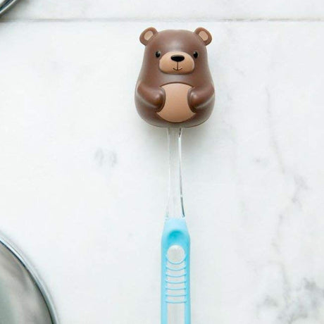 Toothbrush Holder | Bear in brown plastic with suction cup holding a blue toothbrush on a tile wall.