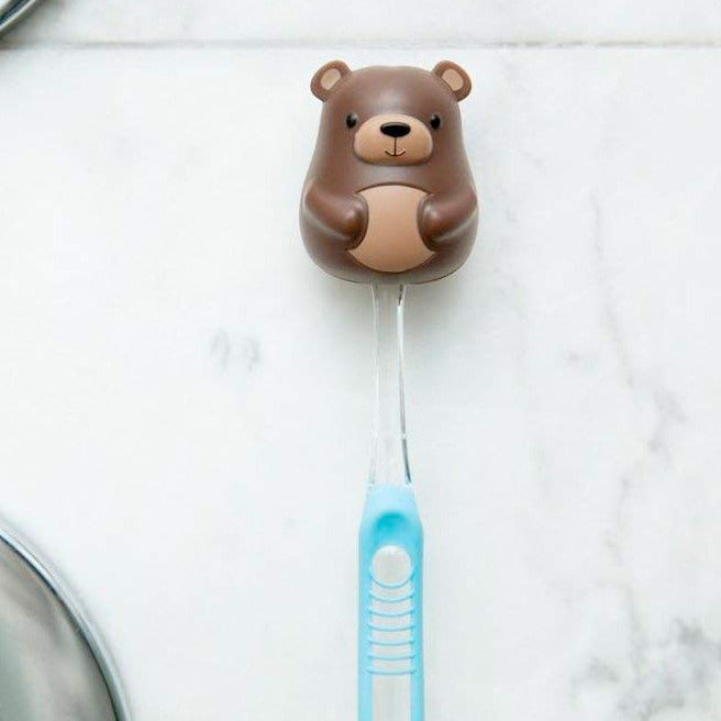 Toothbrush Holder | Bear in brown plastic with suction cup holding a blue toothbrush on a tile wall.