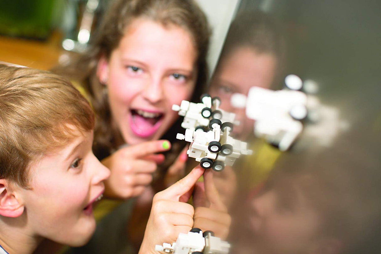 Children playing with the Fridge Rover magnetically moving along a fridge surface, showcasing its wind-up mechanism in action.