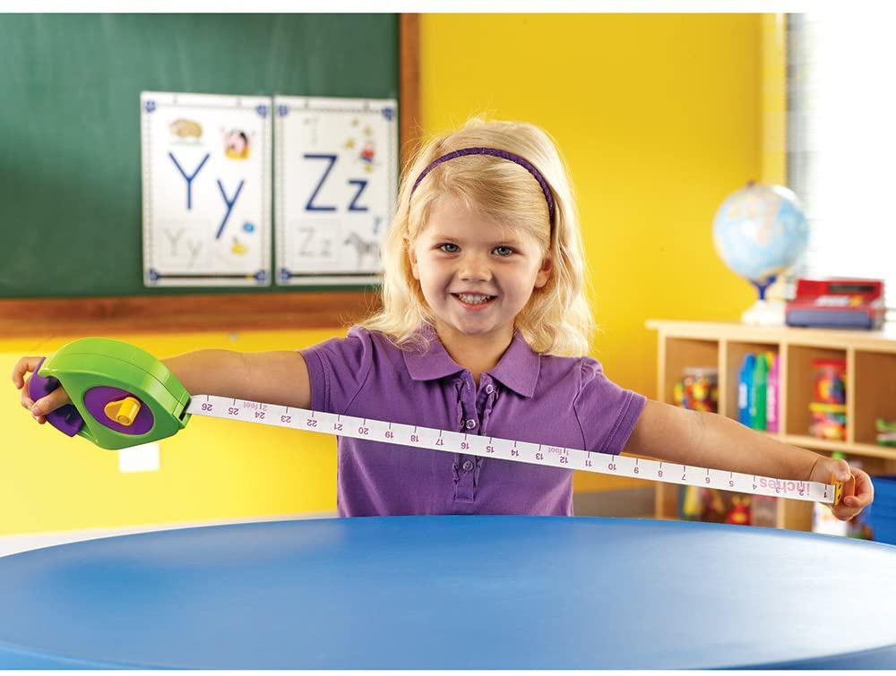 Tape Measure held by smiling child measuring at school, showing manual-wind tape with inches and centimeters.