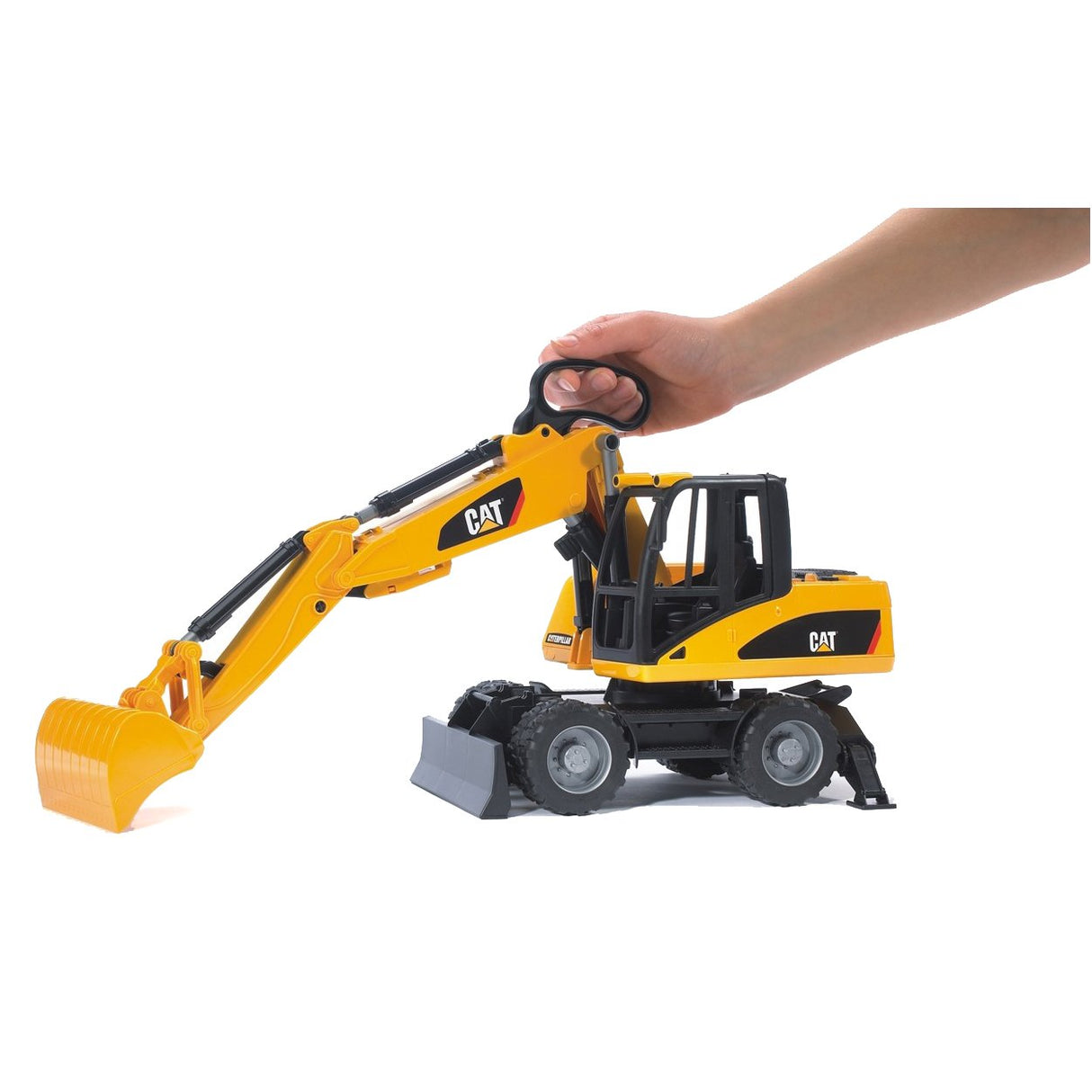 Hand operating the yellow CAT Wheeled Excavator toy with movable arm and shovel on white background.