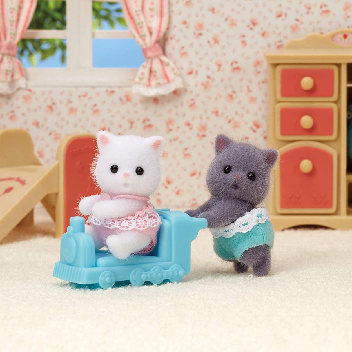 Persian Cat Twins with two fluffy Persian Cat babies in fabric clothes and a blue ride-on toy in a cozy playroom.
