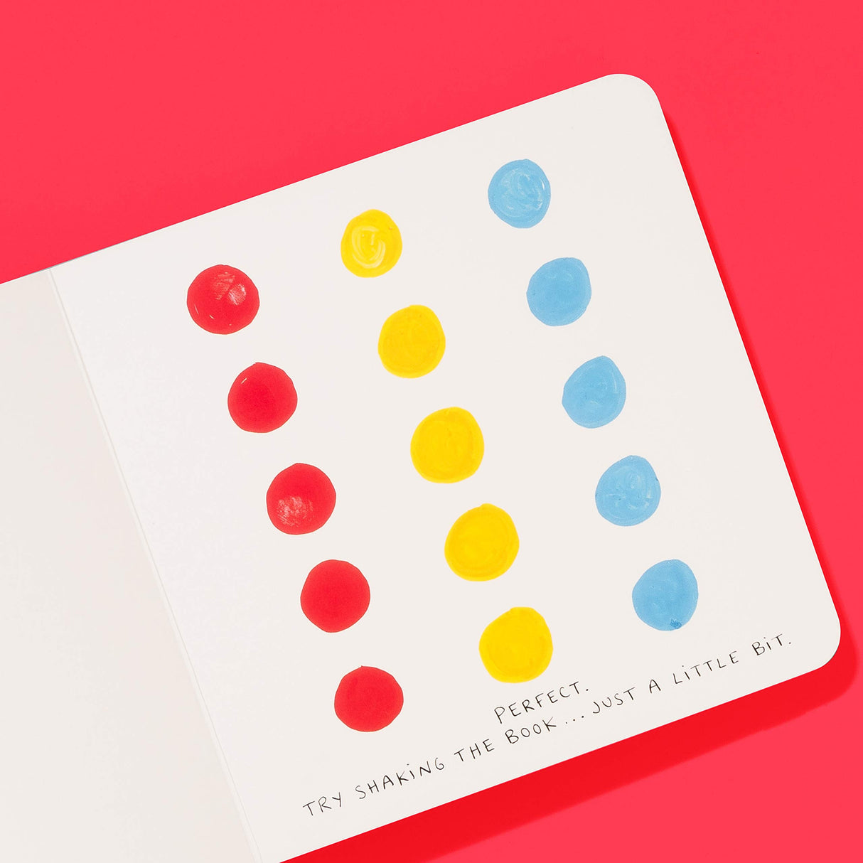 Open page of the Press Here book showing colorful red, yellow, and blue dots on white background with playful instructions.