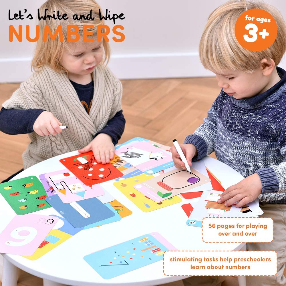 Children using Let's Write & Wipe Numbers educational cards to trace and learn numbers with markers at a small table.
