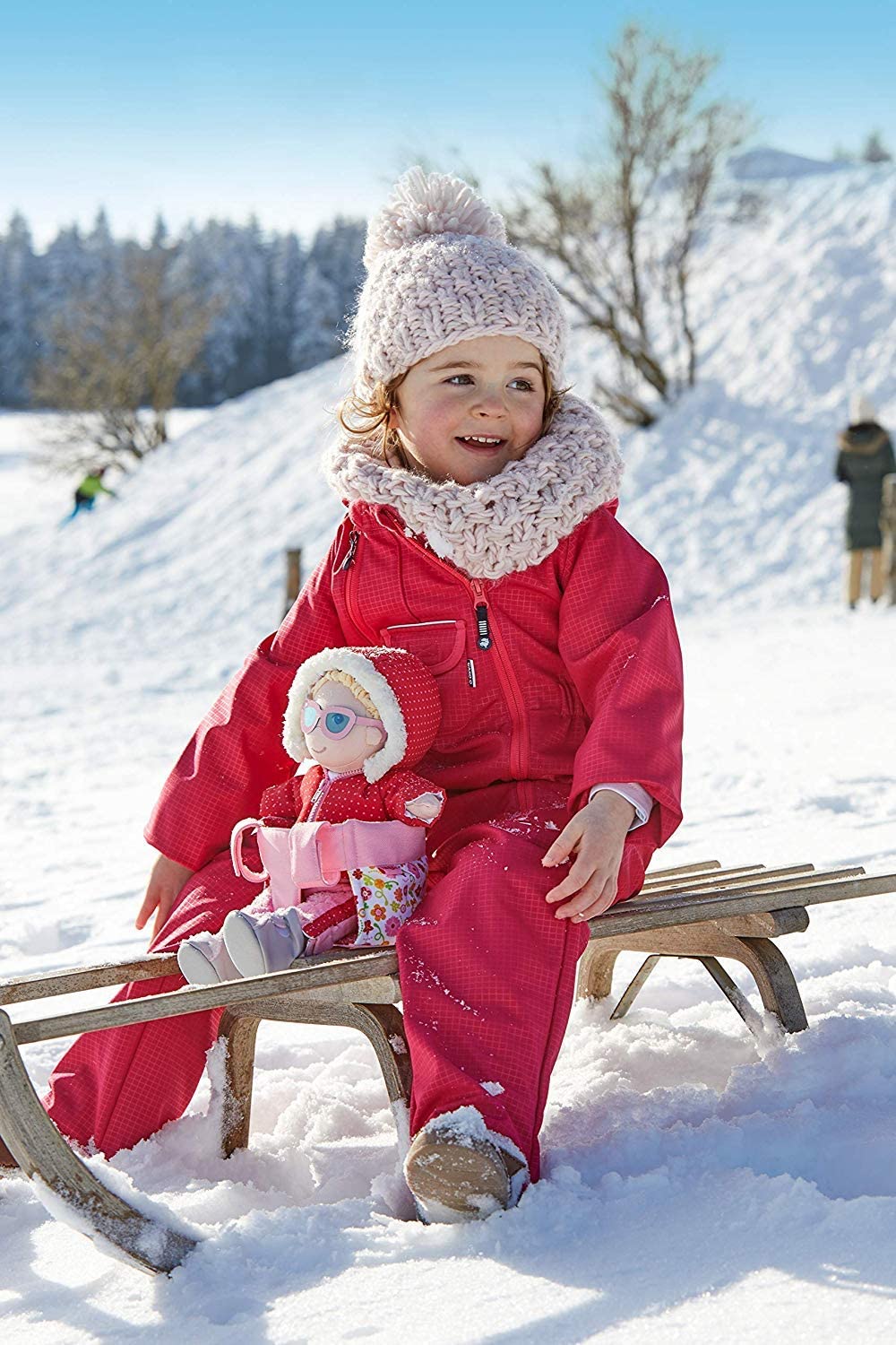 Doll's Bicycle Seat securely attached to a sled with a child in winter clothes holding a doll outdoors in snow
