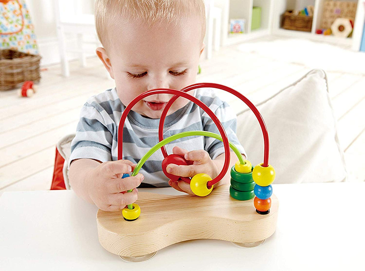Toddler playing with Double Bubble Bead Maze, moving colorful wooden beads along wire tracks attached to a wooden base.