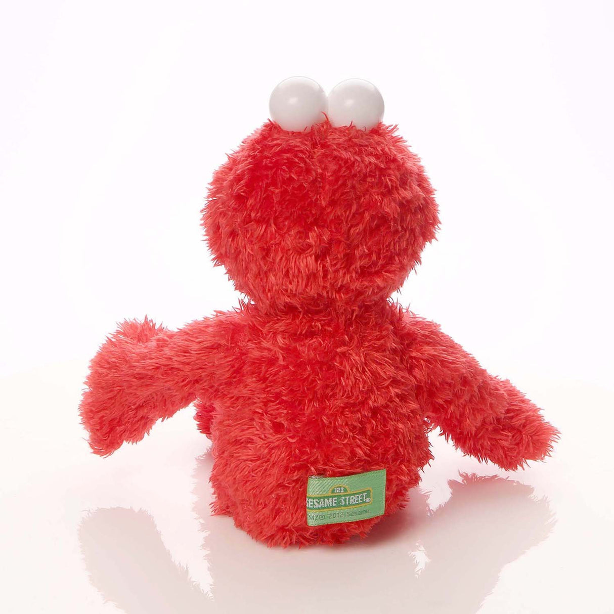 Elmo plush showing back view with fluffy red fur and Sesame Street tag, perfect for cuddling and decoration.