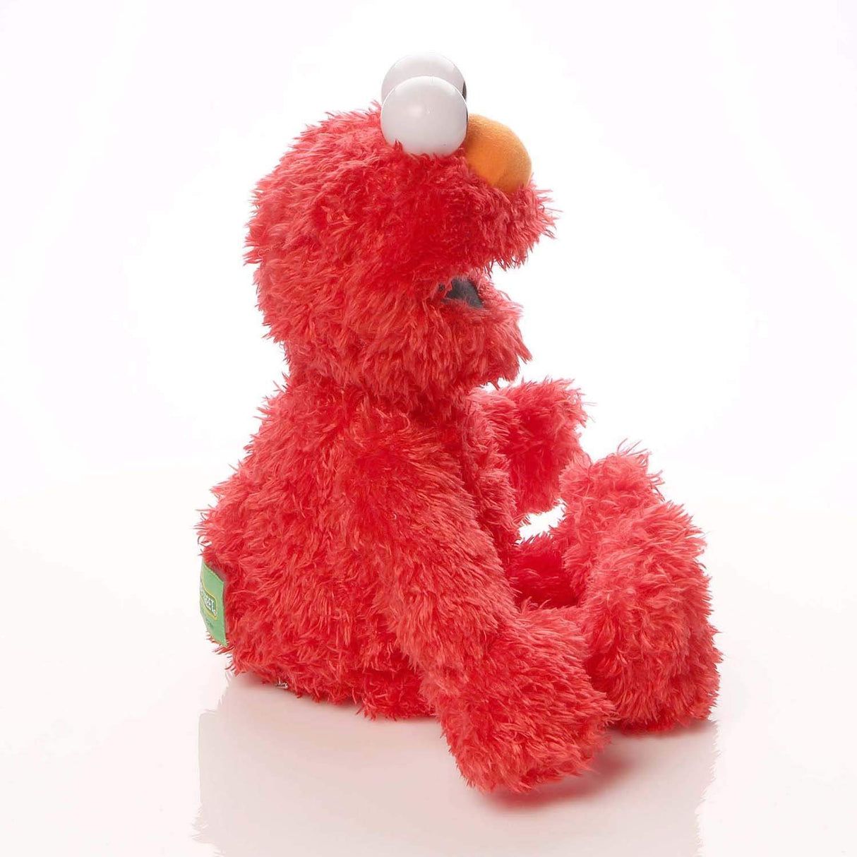 Elmo plush sitting sideways showing soft red fur and orange nose in 13 inch GUND Sesame Street toy.