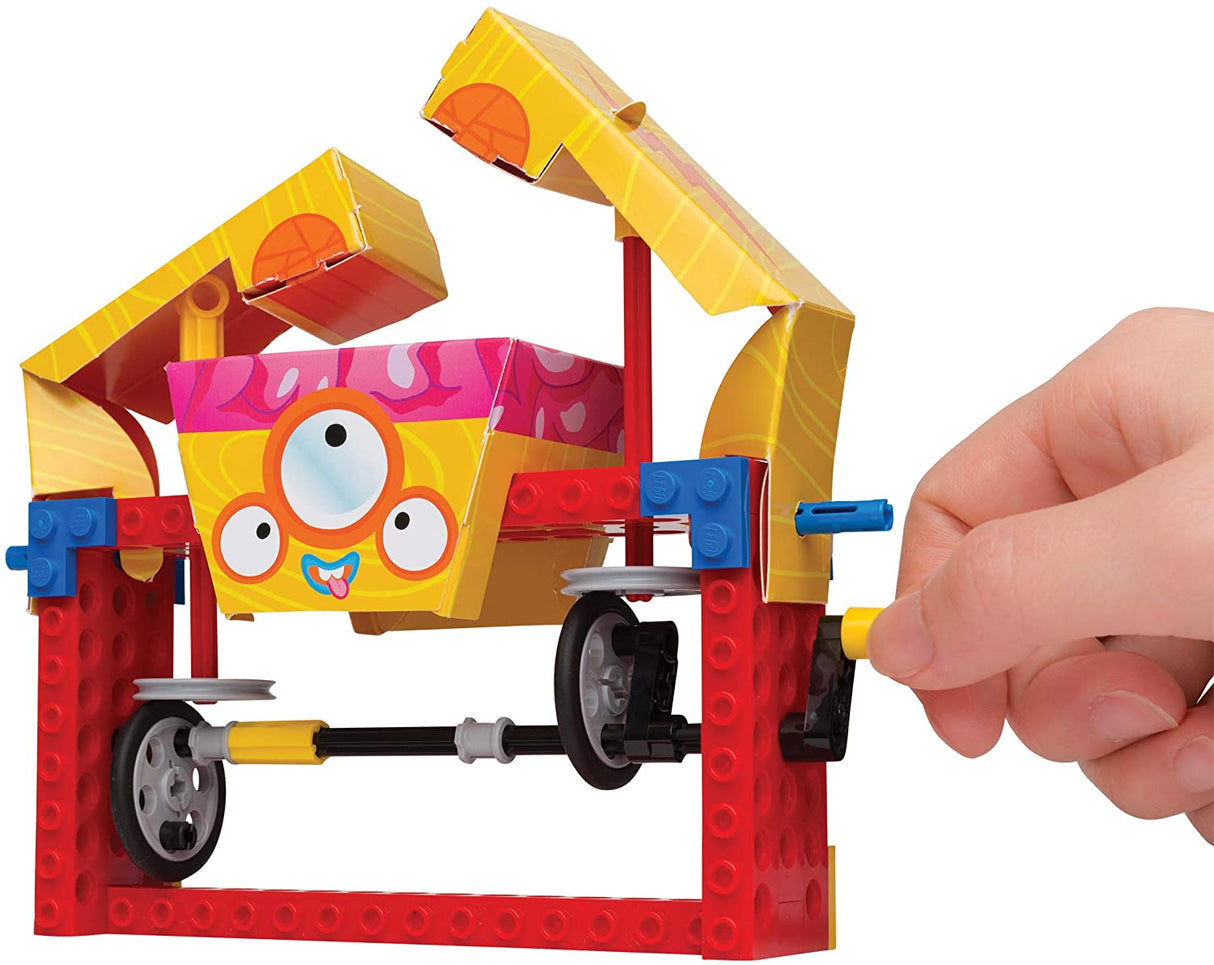 Hand cranking a colorful mechanical model with paper character from Lego Gear Bots STEM toy set.