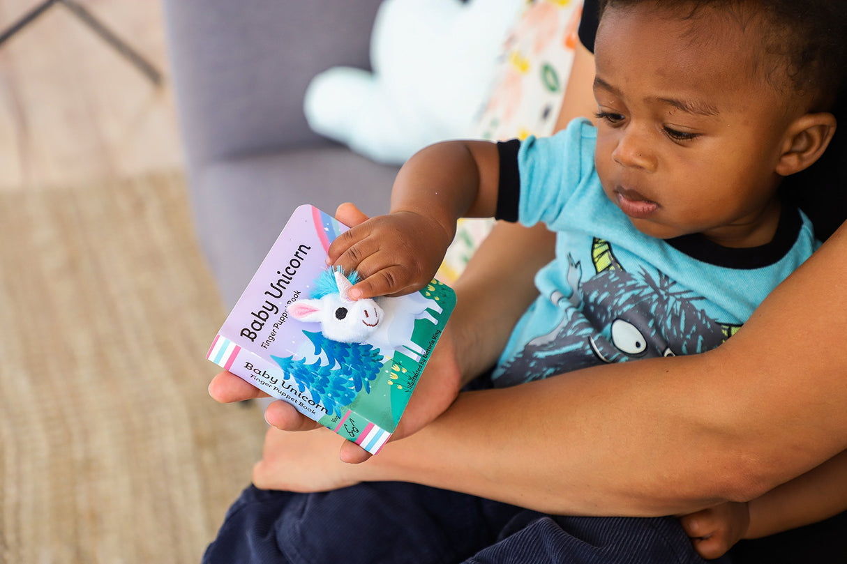 Baby Unicorn with Finger Puppet shows a toddler engaged with the soft finger puppet book featuring colorful illustrations.