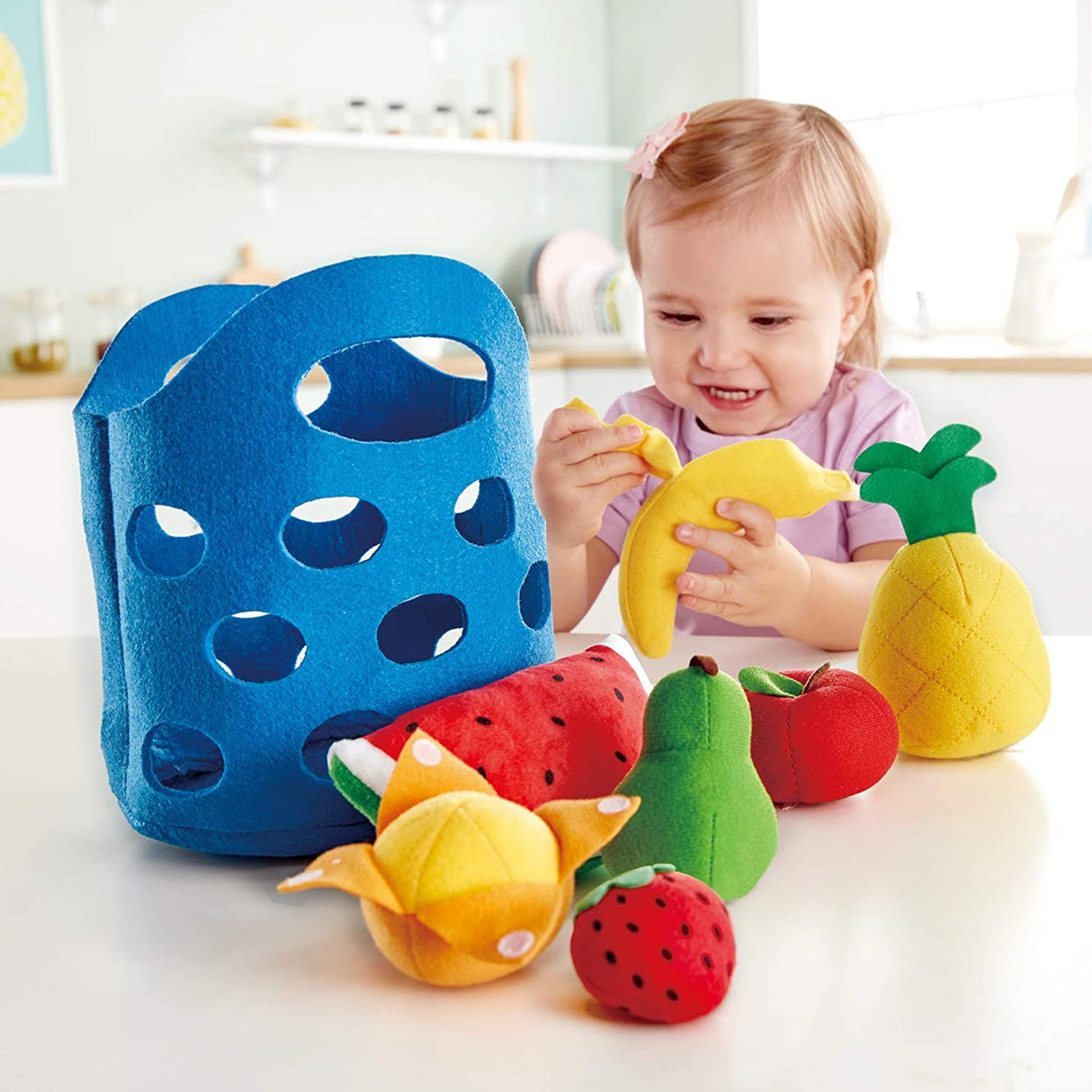 Toddler playing with colorful felt fruits including pineapple and banana in the Fruit Basket shop playset.