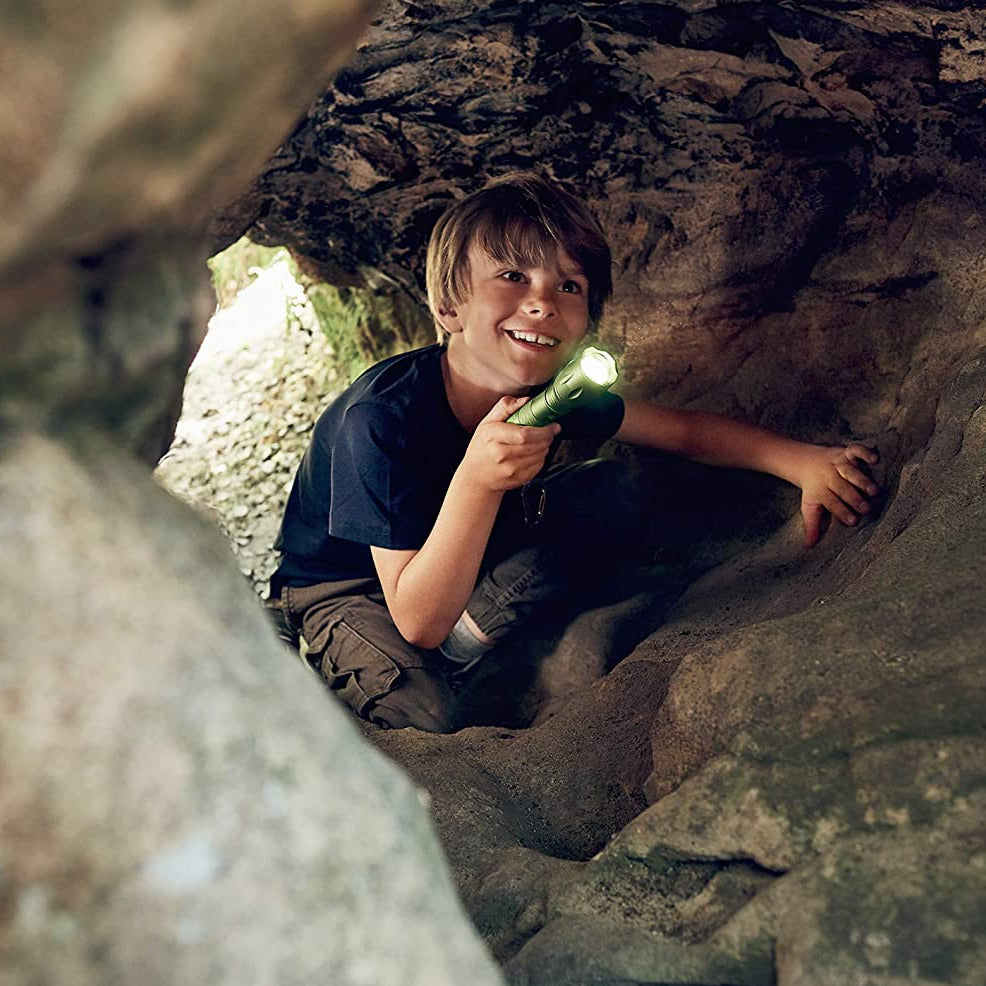 Young boy exploring a cave holding a bright Exploration Flashlight lighting up the dark path safely.