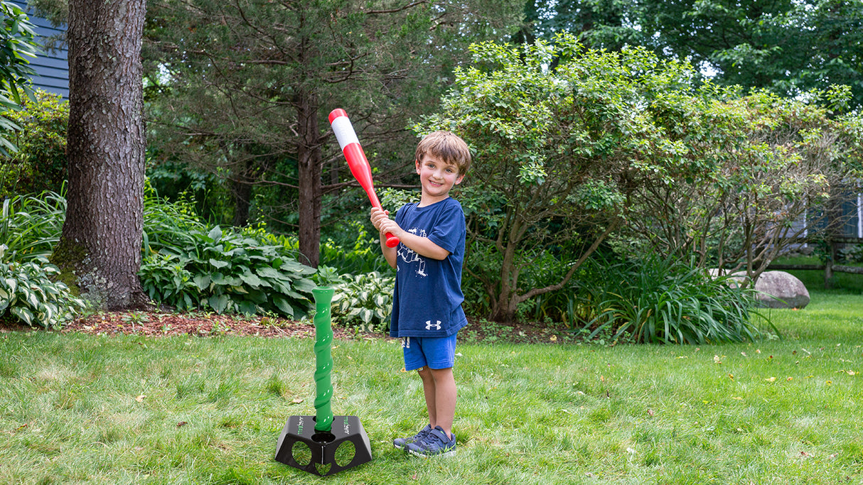 Child playing baseball outside with the Junk Ball T Ball Set featuring adjustable height and bat with sweet spot.