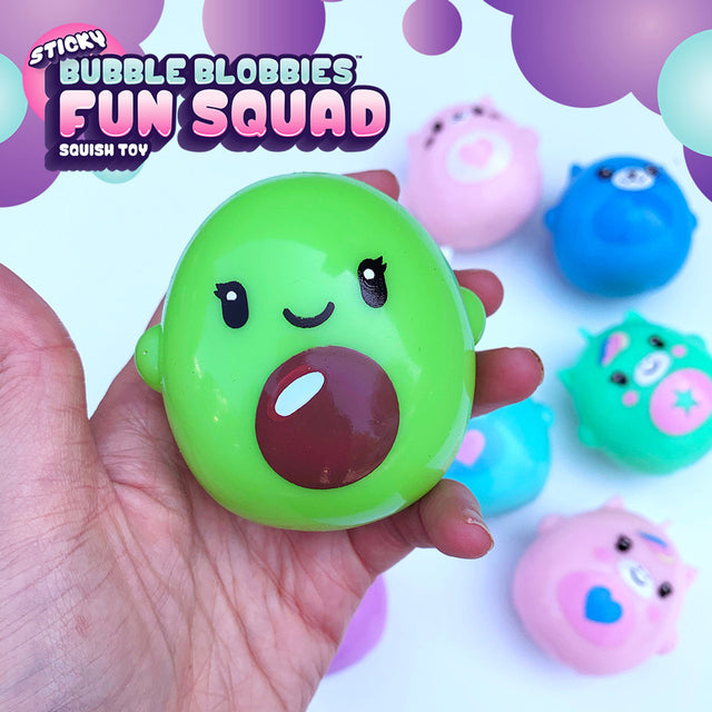 Hand holding a green character from Fun Squad Bubble Blobbie squishy toy collection with other colorful characters in background