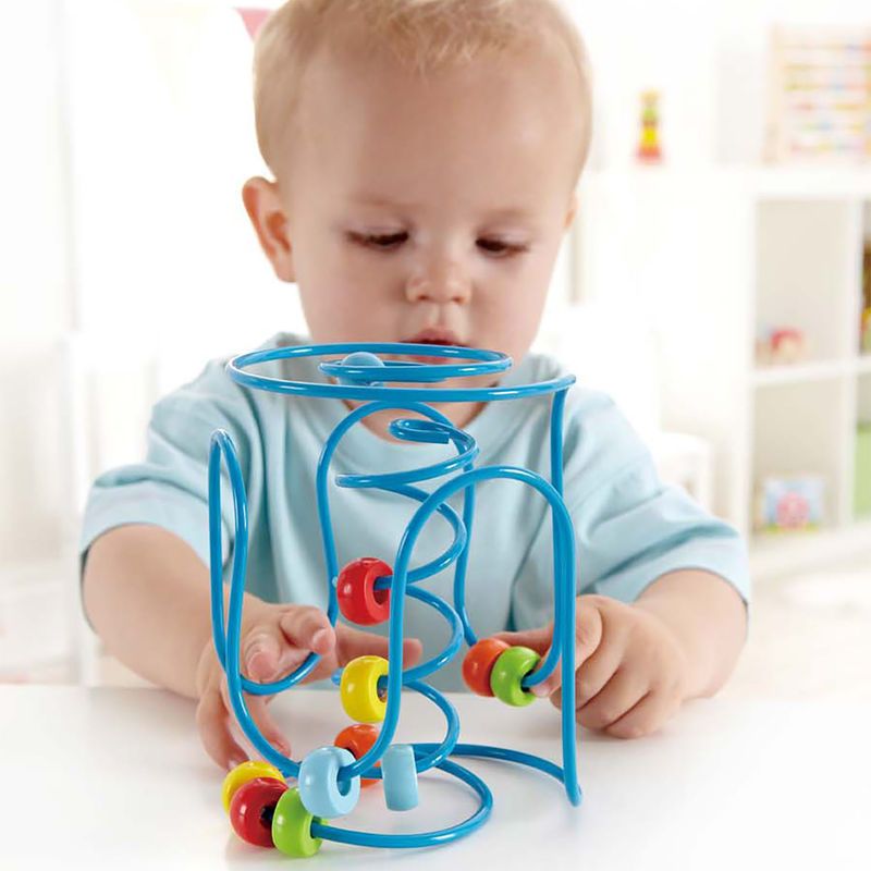Child playing with colorful bead maze toy Spring A Ling designed for ages 6 months and up.