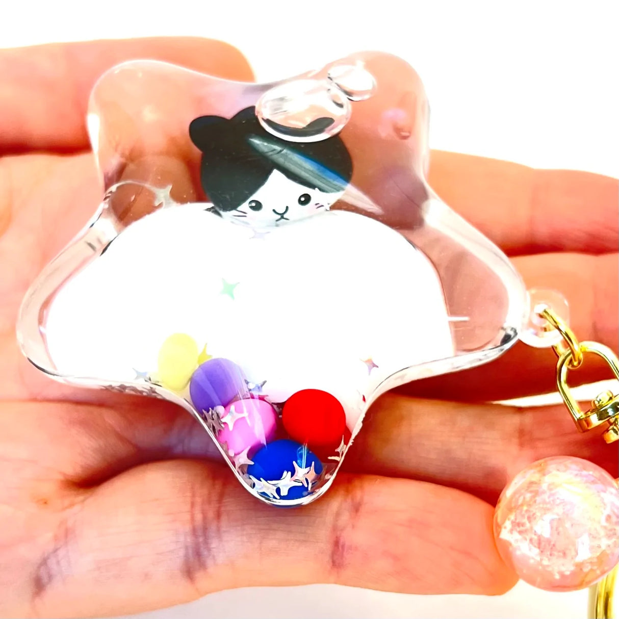 Kitty Star Keychain with colorful beads inside clear star-shaped charm held in hand with gold keyring clip.