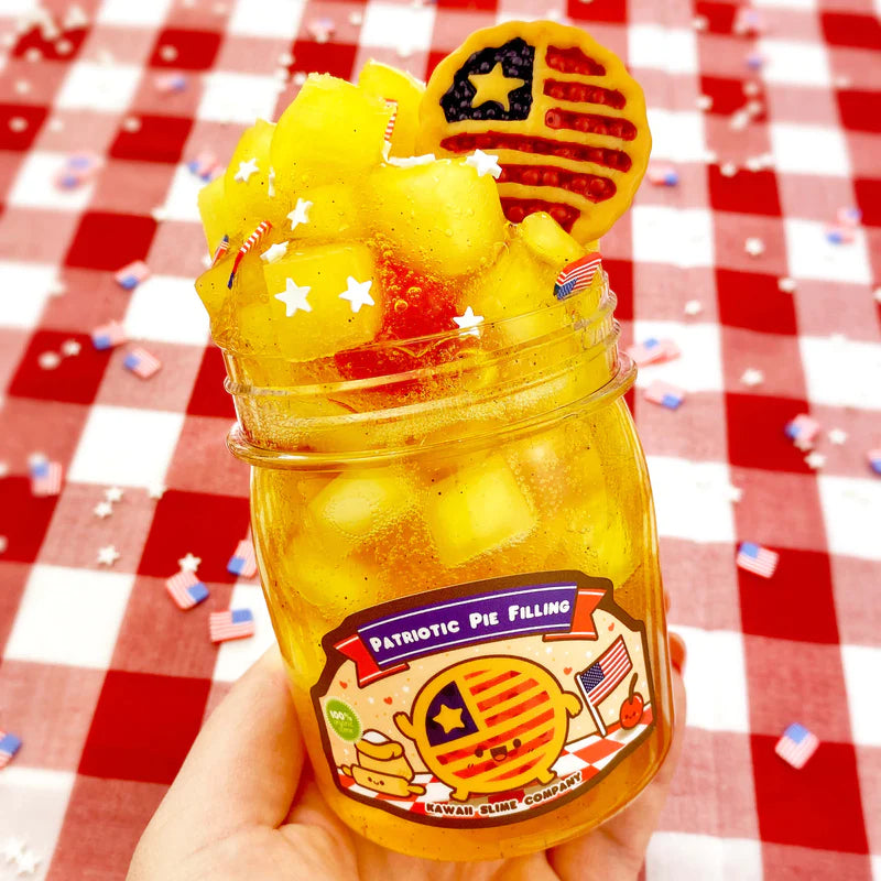 Patriotic Pie Filling Jelly Cube Slime in jar with yellow jelly cubes, star decorations, and American flag charm on red checkered tablecloth