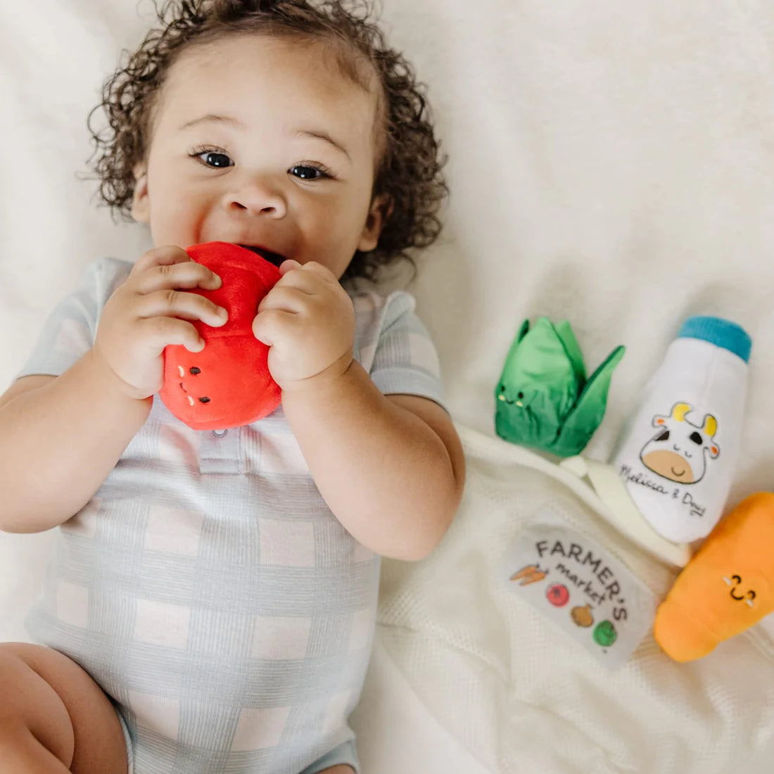 Baby playing with plush toys from the Fill & Spill Market Basket including tomato, lettuce, milk bottle, and carrot