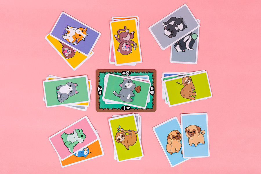 May Contain Butts card game with colorful animal front and butt matching cards on pink background.