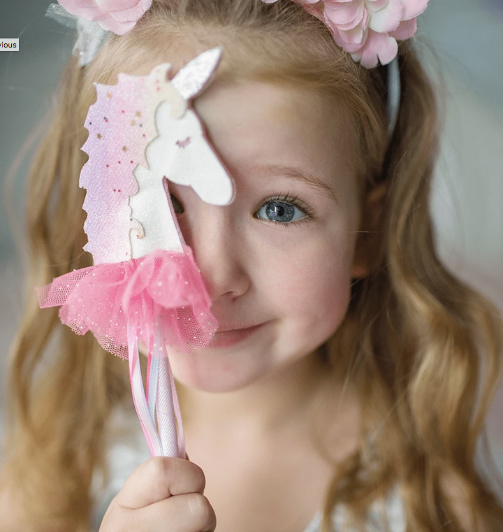 Child holding a Fanciful Unicorn Wand with pink tulle and glitter, featuring flowing ribbons and a unicorn design.