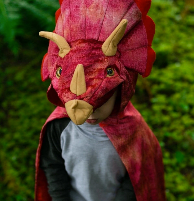 Child wearing a red Triceratops Hooded Dinosaur Cape with 3D horns and textured velour outdoors.