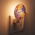 Earth Nightlight glowing softly in a wall outlet showing a realistic 3D printed photo of the earth at night.