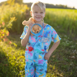 Child wearing Veterinarian Set scrubs holding plush puppy with cone and toy syringe outdoors at sunset.
