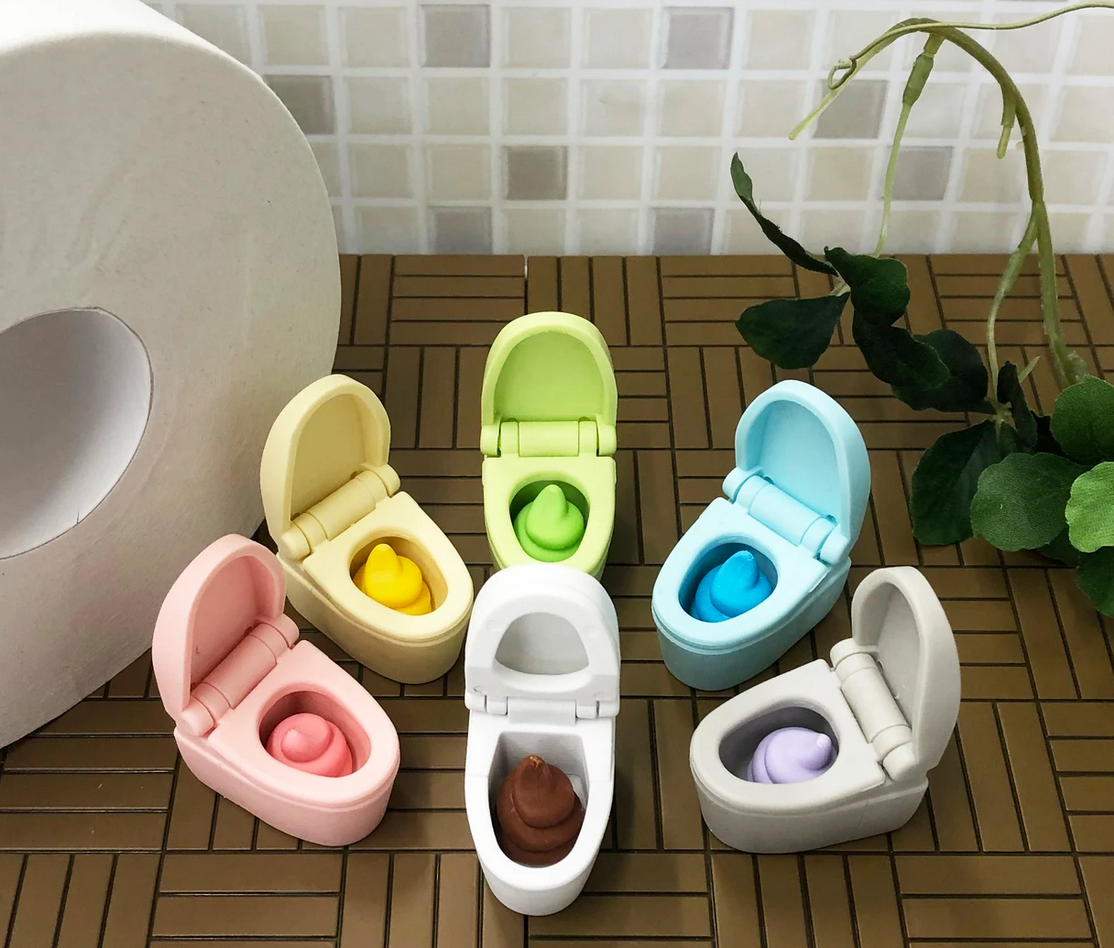 Japanese Eraser Toilet puzzle erasers in assorted colors with removable poo, displayed on a wooden surface with greenery.
