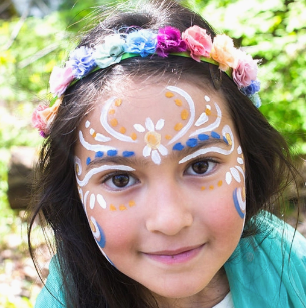 Young girl with colorful face paint design wearing a flower crown using Face Paint Kit - Natural outdoors.